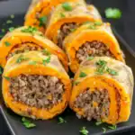 Roasted Butternut Squash Stuffed with Quinoa and Ground Beef, garnished with fresh herbs, served on a black plate for a nutritious and colorful meal.