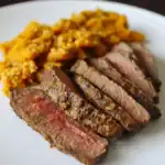 Juicy grilled steak with a peppercorn crust served with savory quinoa on a white plate. Perfect for a gourmet meal or special occasion, highlighting premium quality beef and flavorful grains.