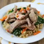 Juicy grilled chicken on a bed of quinoa, sautéed spinach, and carrots, served on a white plate. Healthy, flavorful, and nutritious meal, perfect for a balanced diet.
