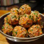 Fried vegetarian meatballs garnished with chopped parsley in a black bowl, served on a wooden table, showcasing delicious plant-based cuisine from Waggy Chef.