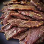 Thinly sliced seasoned beef jerky with spices and herbs, perfect for dog treats or healthy snacks.