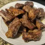 Juicy, seasoned beef short ribs with a flavorful crust, cooked to perfection and served on a white plate. Ideal for barbecue lovers seeking tender, flavorful meat.